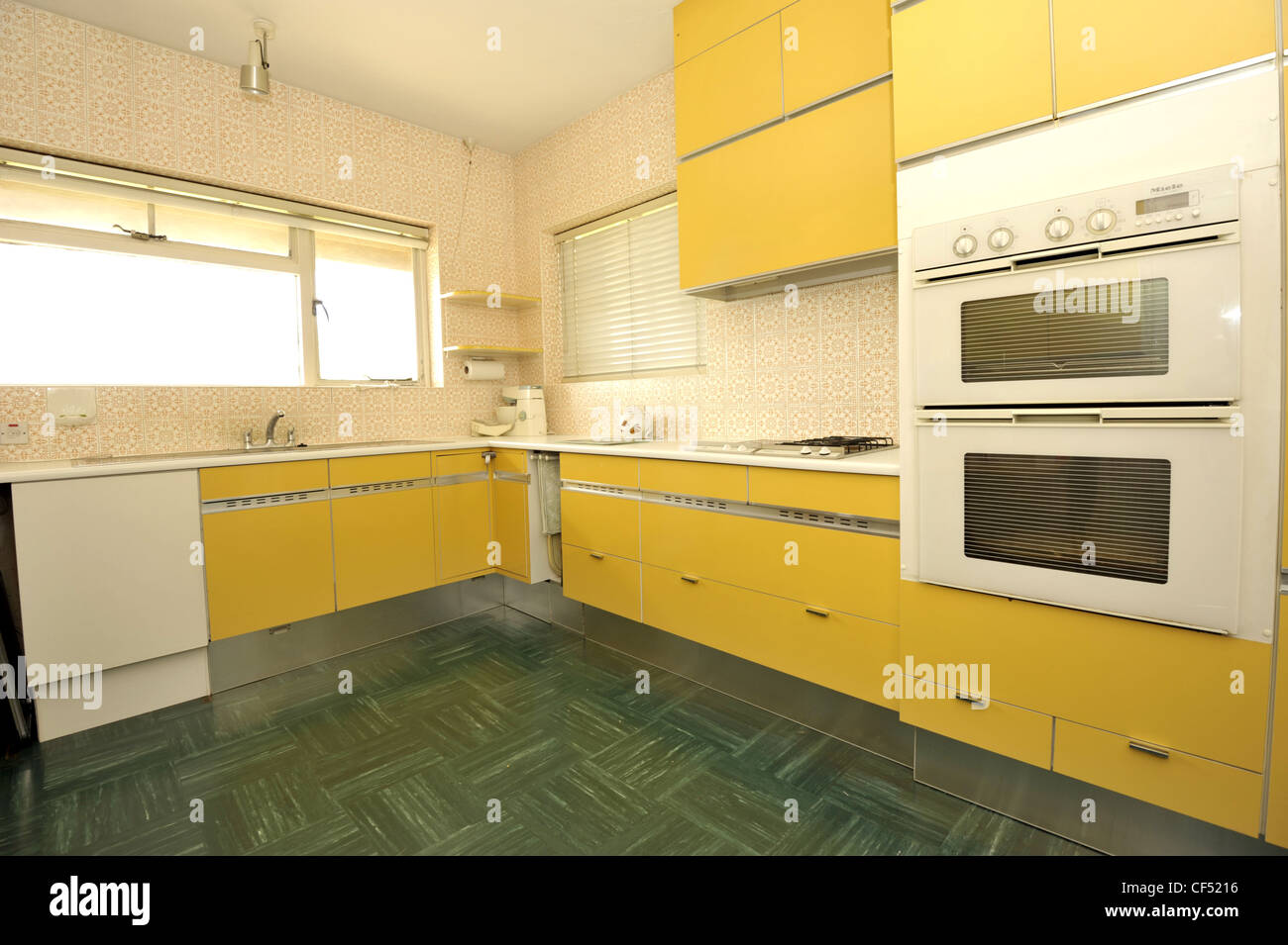 A large kitchen showing yellow cupboards, eyelevel cooker and green
