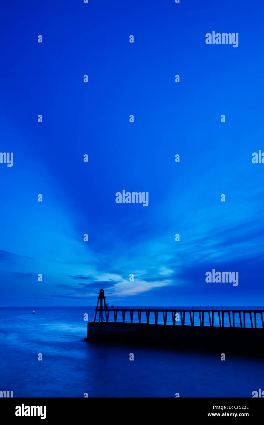 Whitby East Pier Light silhouetted at the end of the East Pier at dawn. Stock Photo