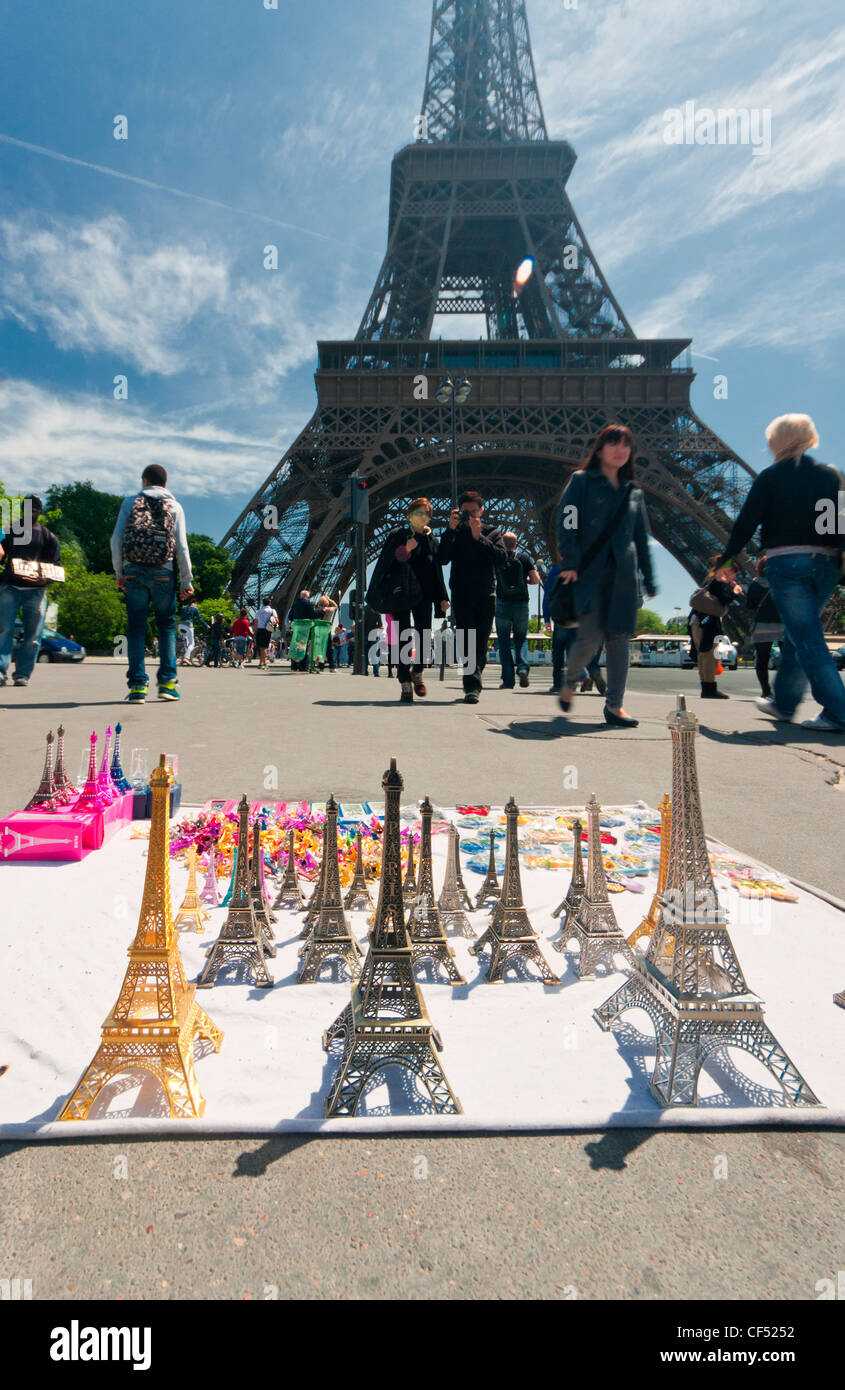 Paris, France. Miniature replicas of the Eiffel Tower in front of the real one, with people passing nearby. Stock Photo