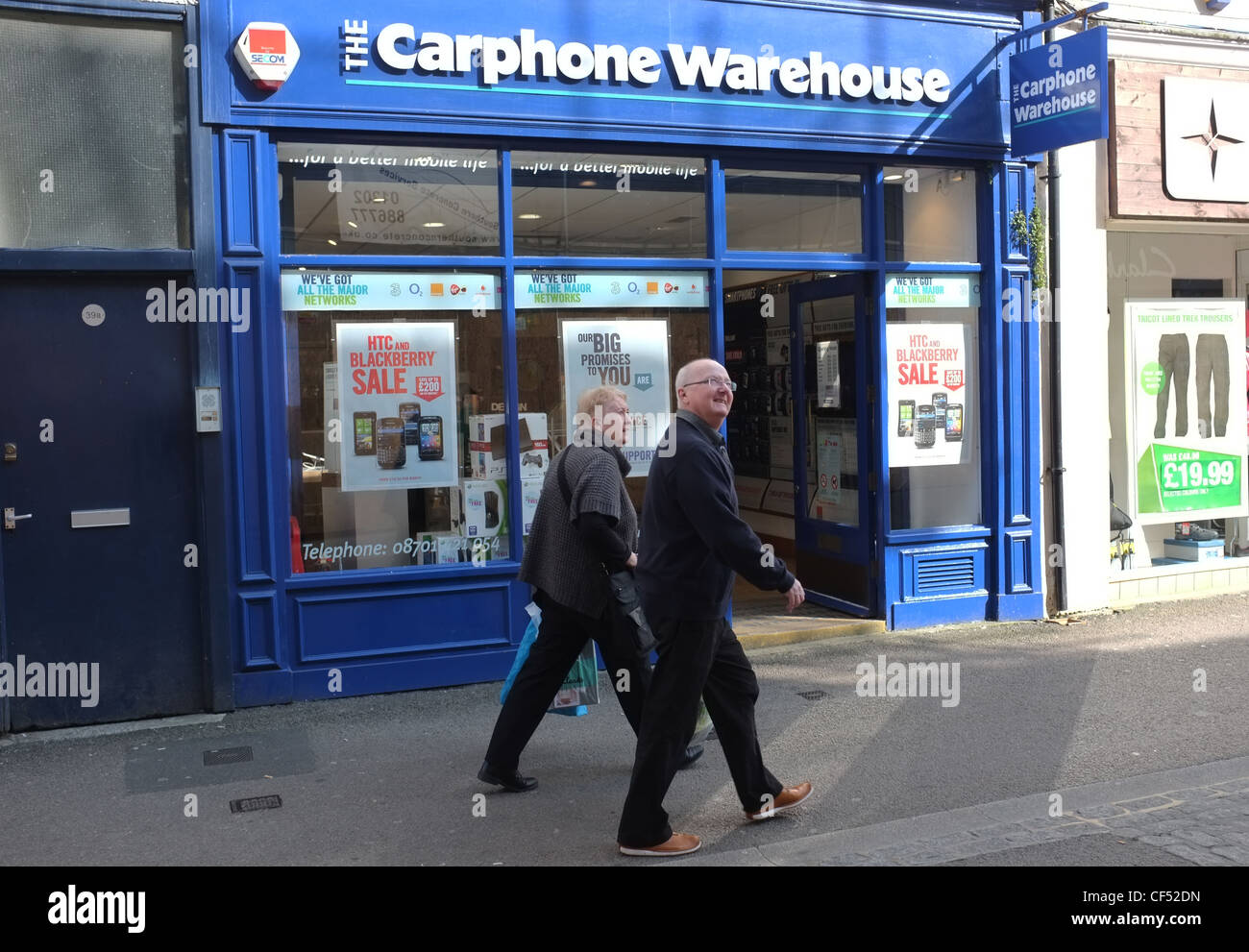 Two older people walk past the Carphone Warehouse in Falmouth, UK Stock Photo