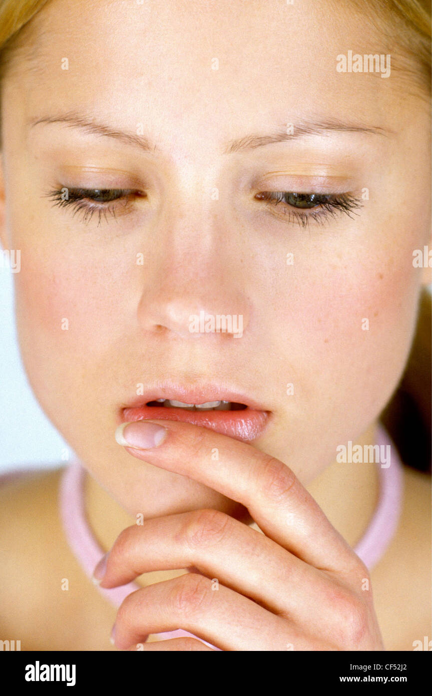 Female with eyes half closed, finger resting on her lower lip Stock