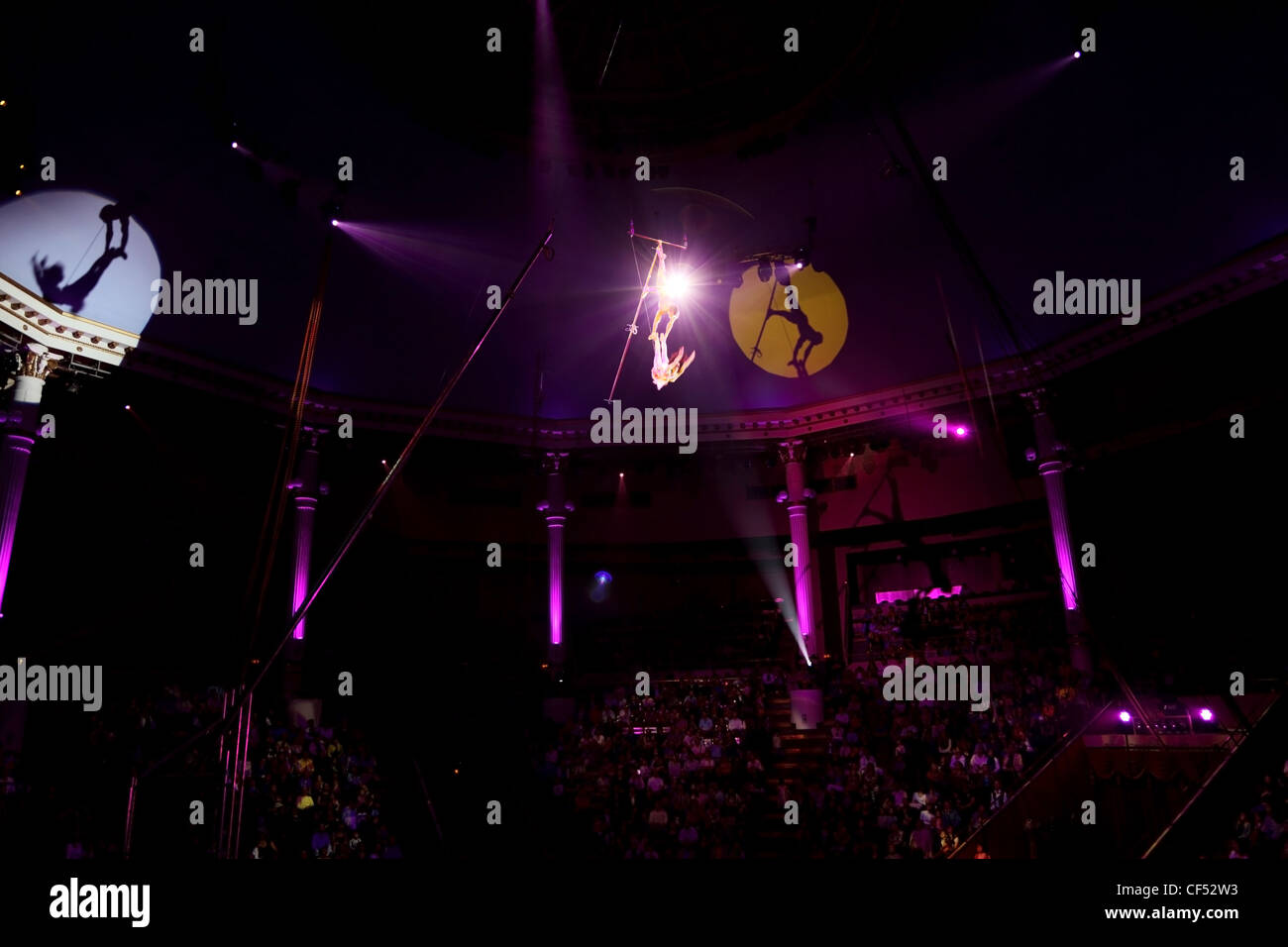 circus performance with two trapeze gymnasts purple light Stock Photo