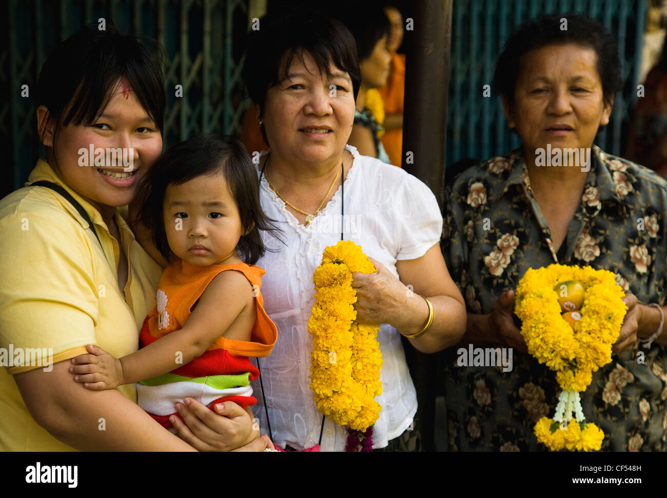 Four female generations of family with floral garlands to celebrate the annual blessing of local temple  Thailand Bangkok Asia Stock Photo