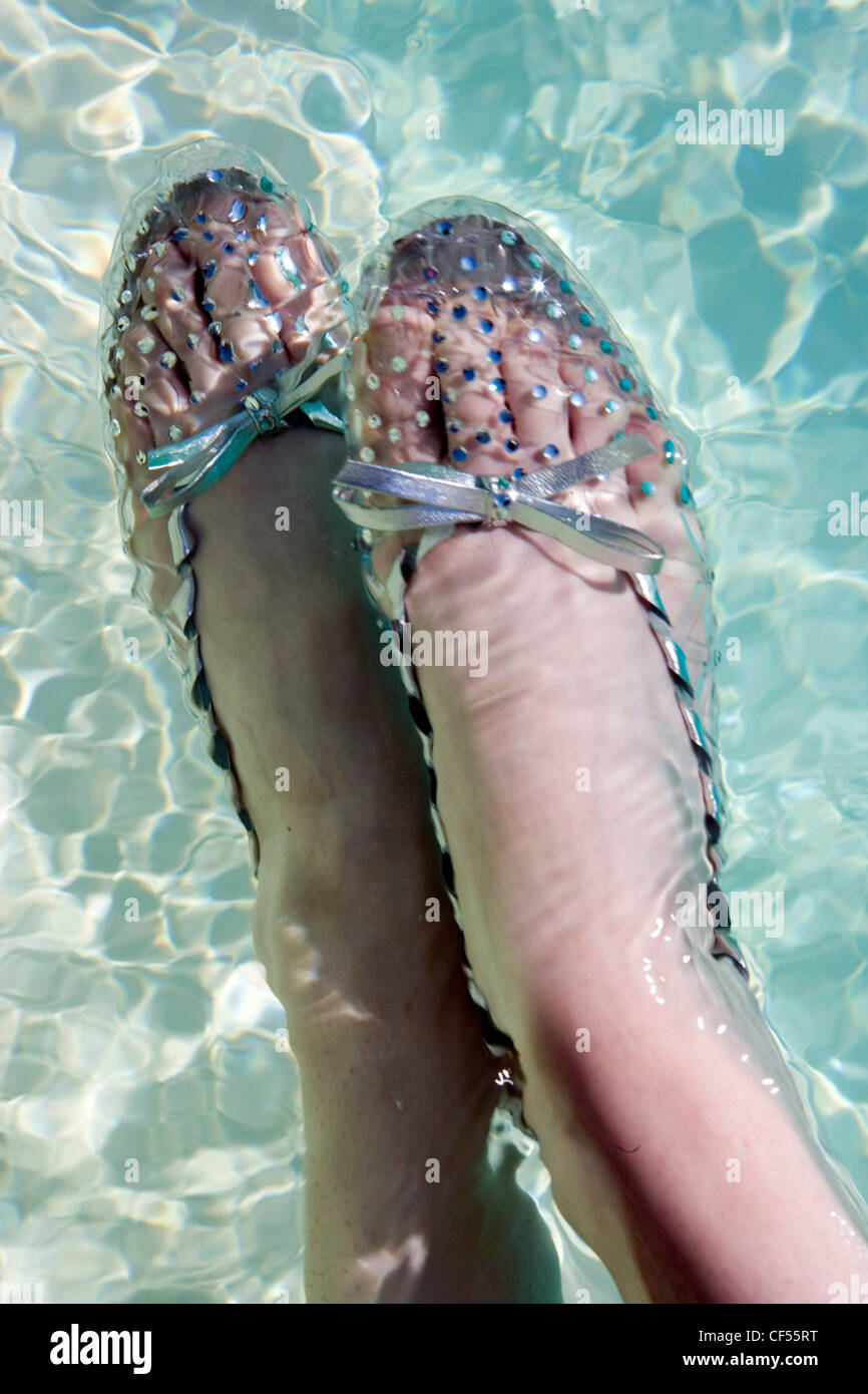 Female feet, clear jelly shoes with sparkle spots, silver bows, feet in  water Freeman Stock Photo - Alamy