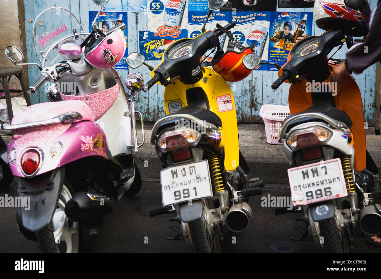 Brightly coloured motorcycle scooters and helmets Thailand Bangkok Asia asian Thailand thai motorcycle motorbike scooter Stock Photo