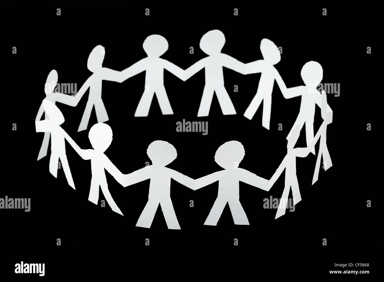 paper little people cutouts dance in ring isolated on black background Stock Photo