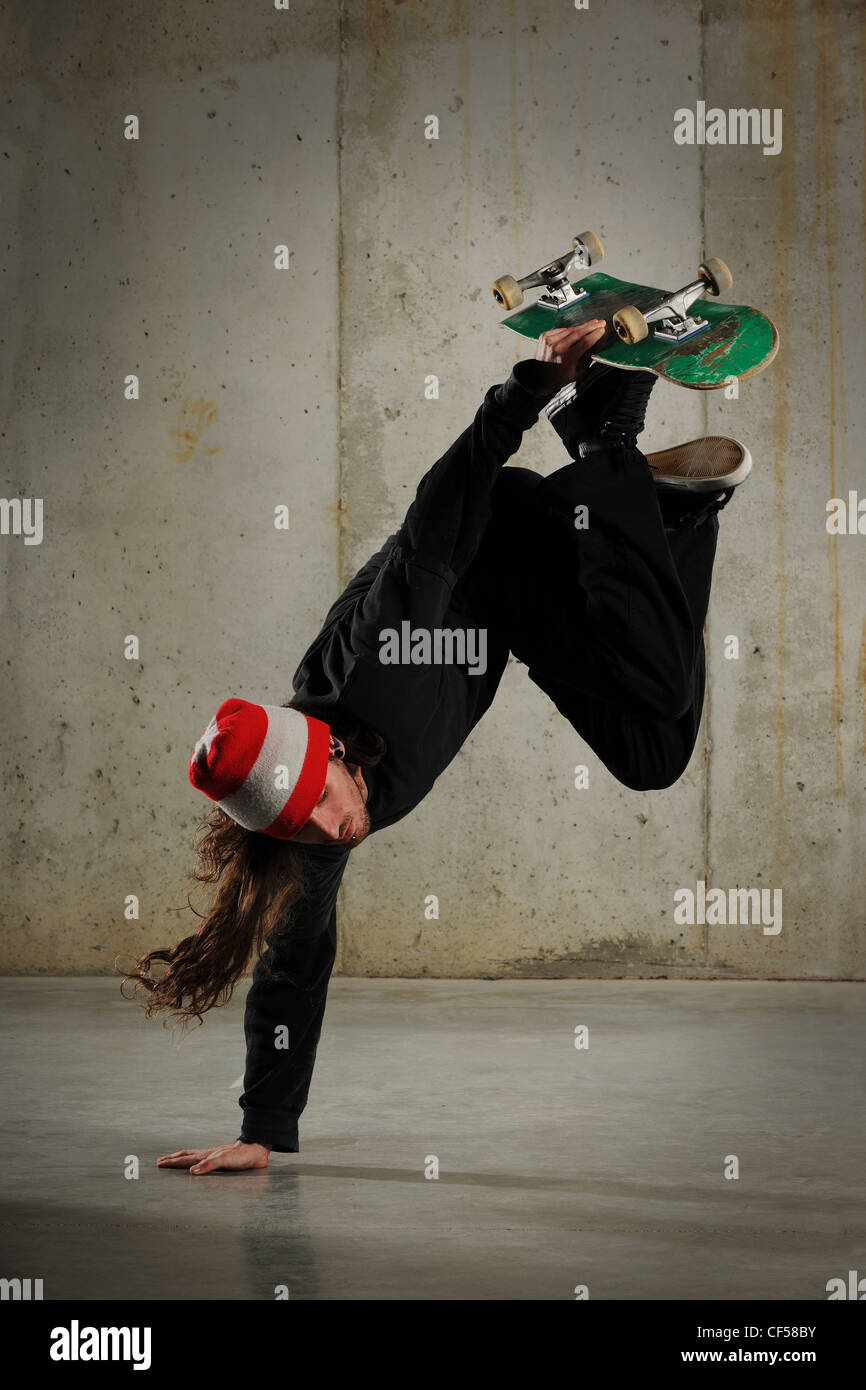 Skateboarder performing tricks with grungy wall as background Stock Photo