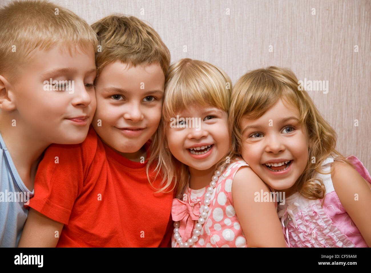 Laughing children four together in cosy room, two pretty girls and two ...