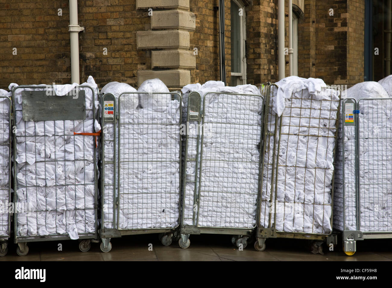 Freshly laundered towels and bed linen in a trolley outside a hotel Stock Photo