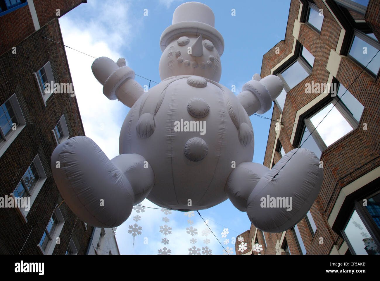 Looking up to a christmas decoration of a giant suspended snowman in Carnaby Street. Stock Photo