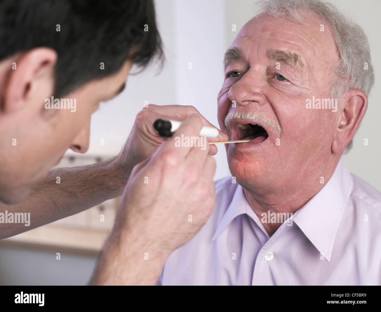 Germany, Hamburg, Doctor examining patient with tongue depressor Stock