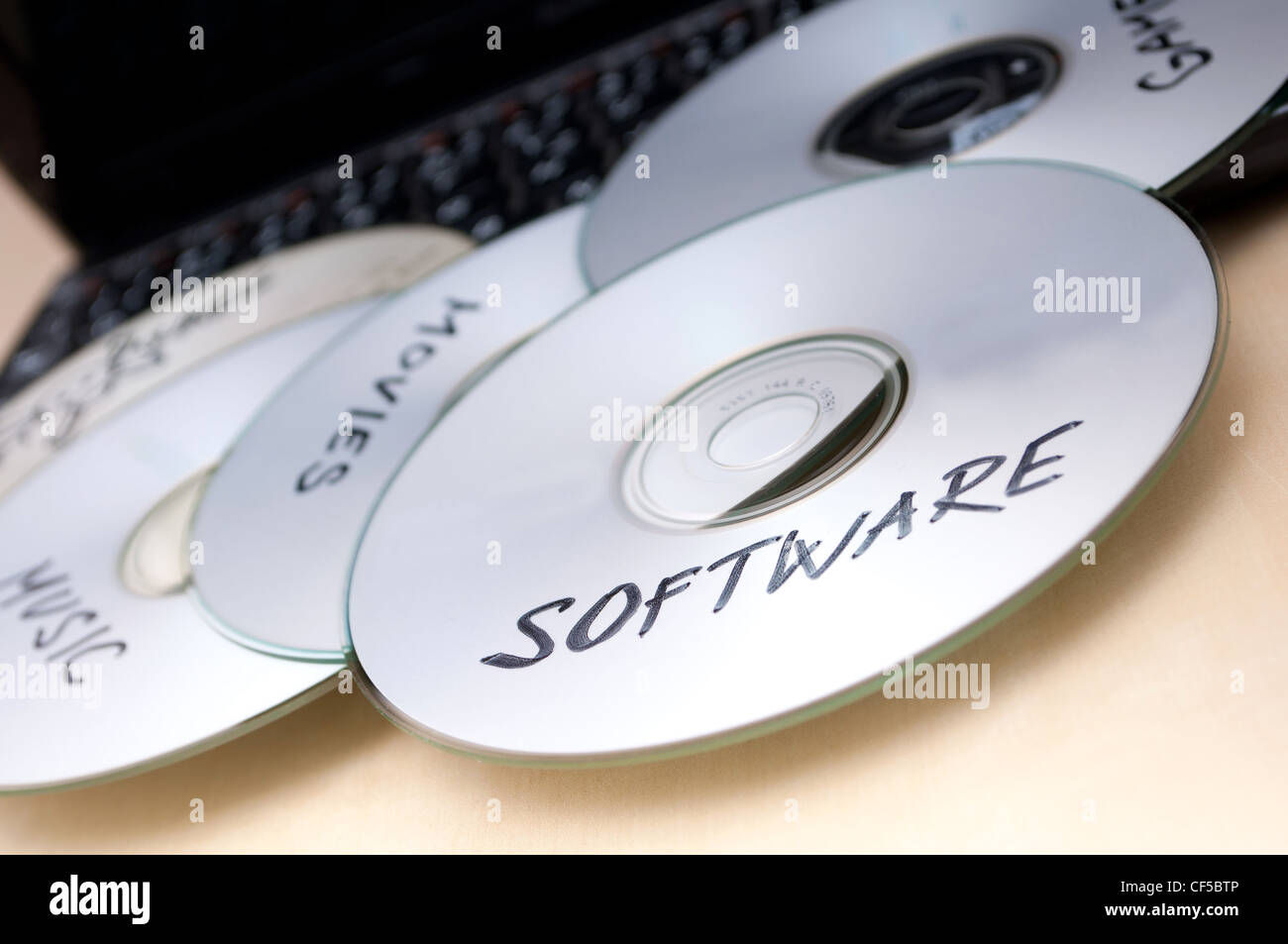 Piracy Concept - Burnt CDs With Illegal Software on Keyboard of Notebook Stock Photo