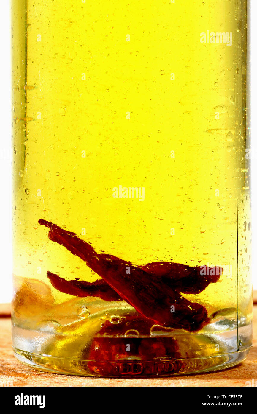 A Glass Bottle Filled With Olive Oil And With Two Dried Chili