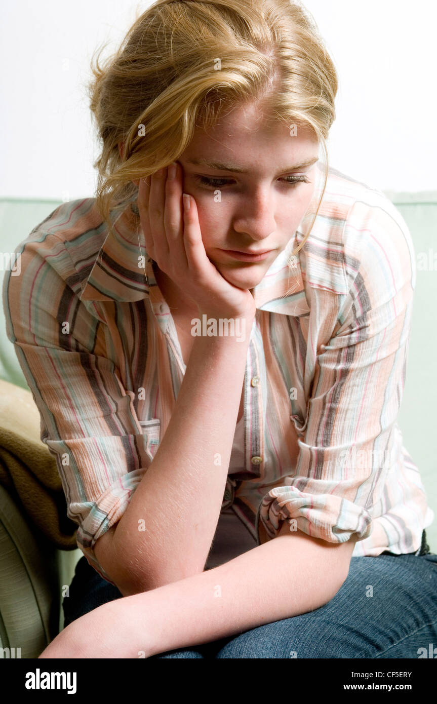 Female sitting on a sofa leaning her head on her hand and resting her