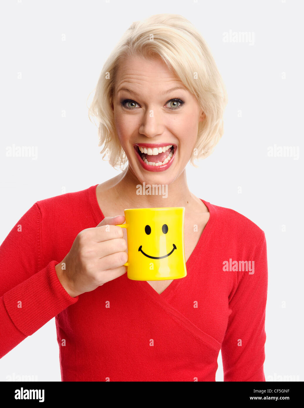 Female holding a yellow mug with a smiley face Stock Photo