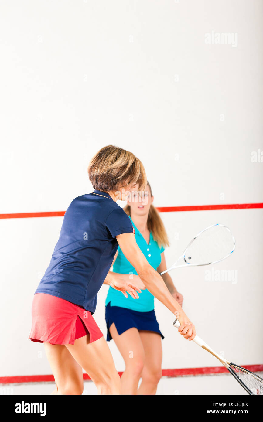 Two women playing squash as racket sport in gym, it might be a competition Stock Photo
