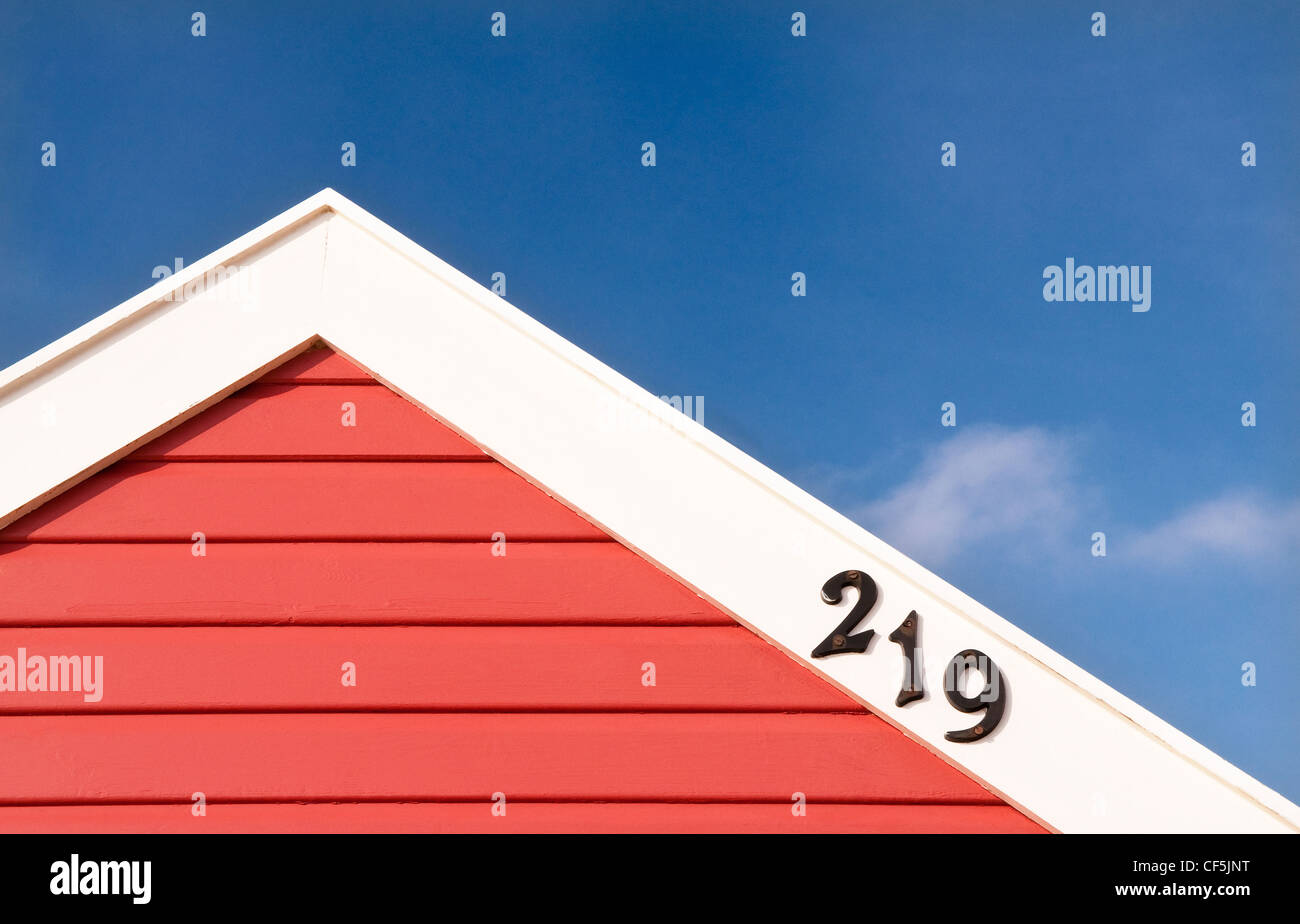 The top of a colourful red beach hut displaying its number, in Southwold. Stock Photo