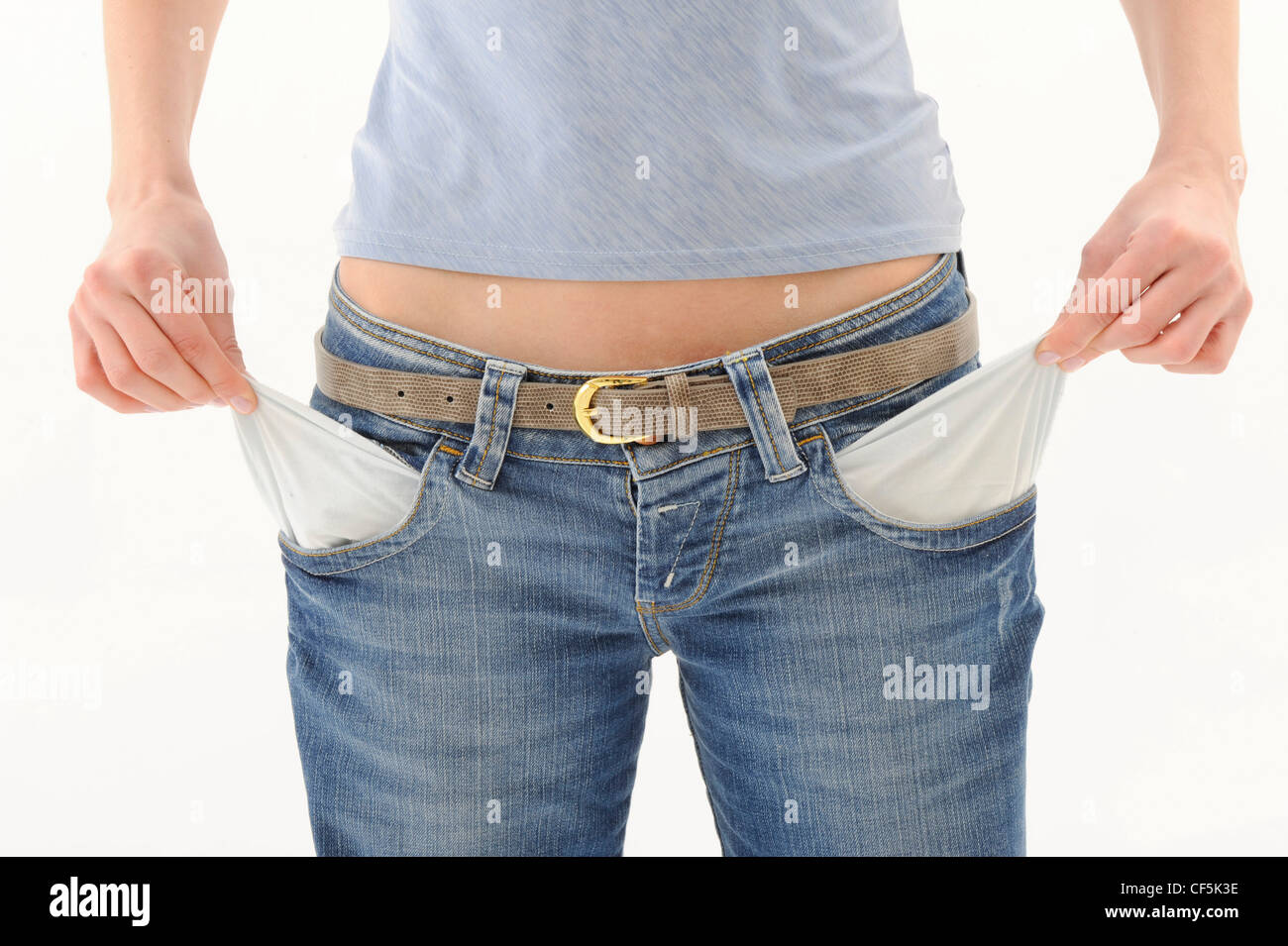 Female wearing a grey top and jeans with brown belt, pulling out empty pockets with both hands Stock Photo