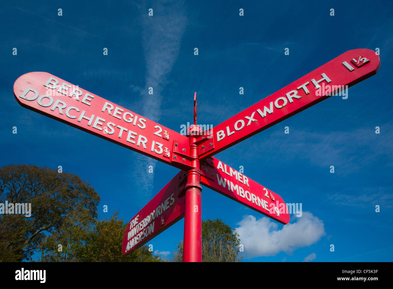 Bright red directional road sign at a crossroads. Stock Photo