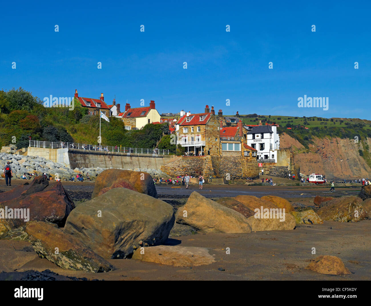 View over large boulders on the beach towards the fishing village of Robin Hoods Bay, the busiest smuggling community on the Yor Stock Photo