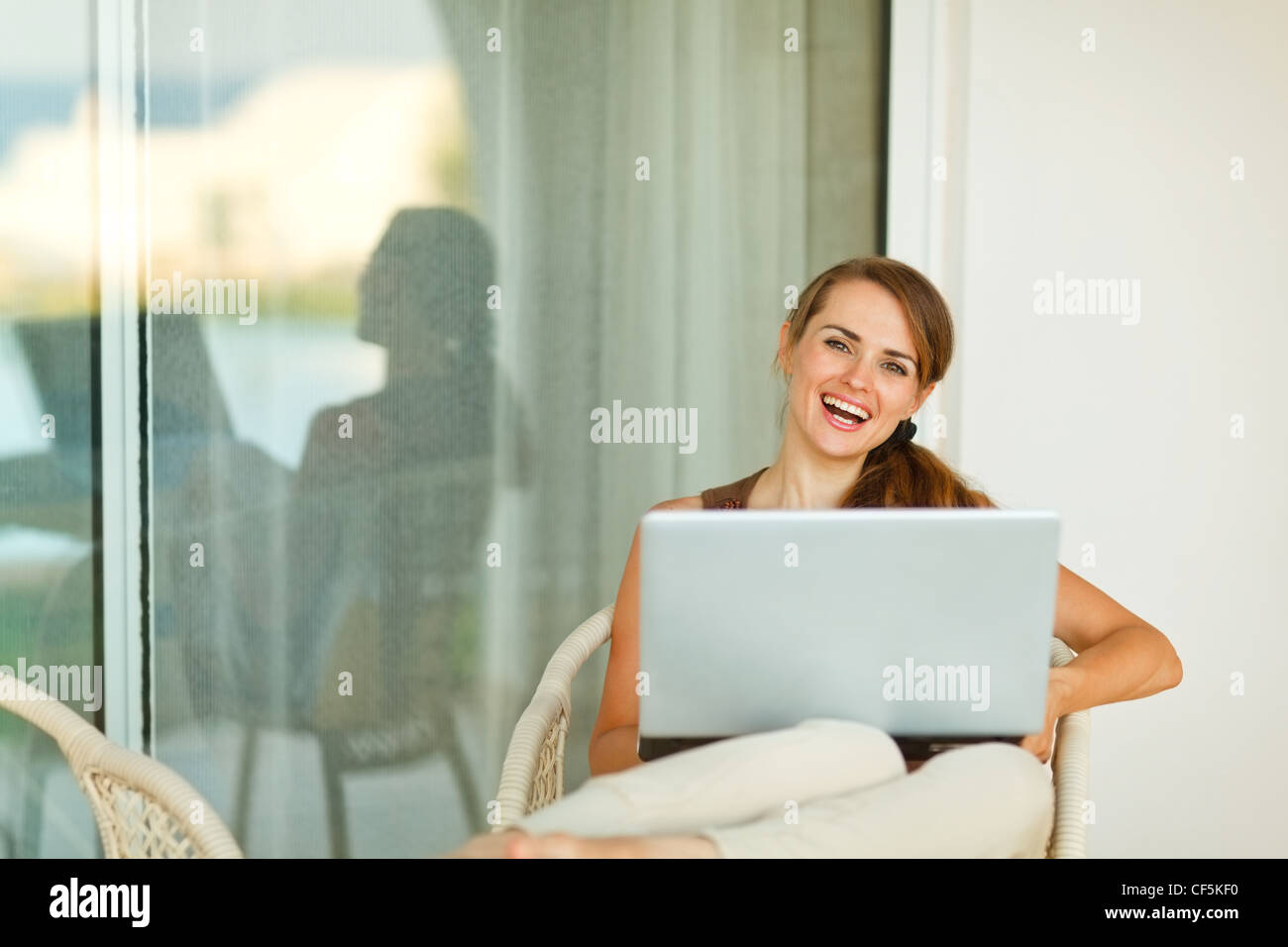 Happy young woman working on laptop on terrace Stock Photo