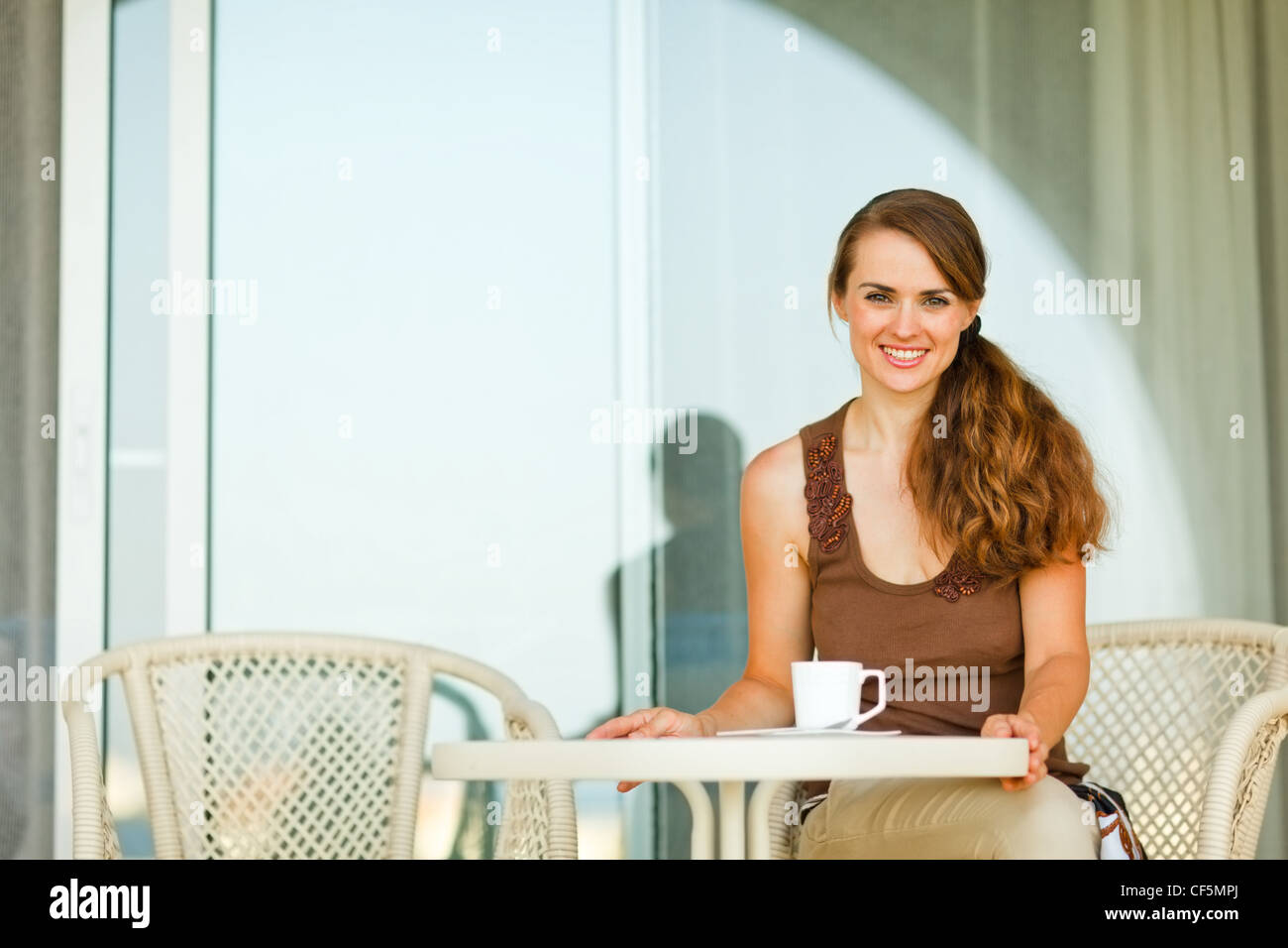 Happy young woman sitting at terrace with cup of tea Stock Photo