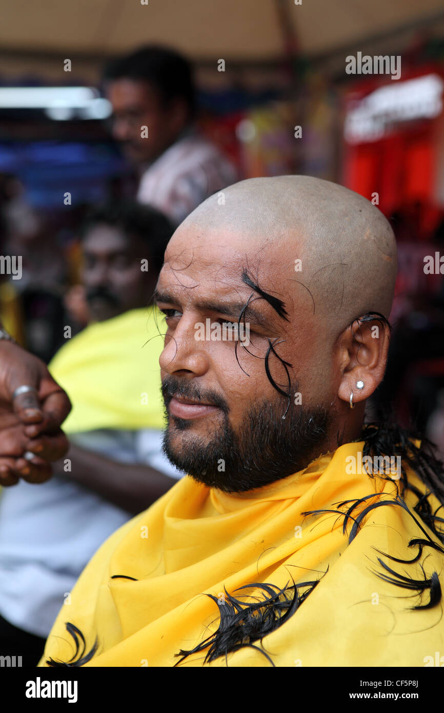 Devotee having hair shaved off during Thaipusam Hindu festival at Batu Caves in Kuala Lumpur, Malaysia Stock Photo
