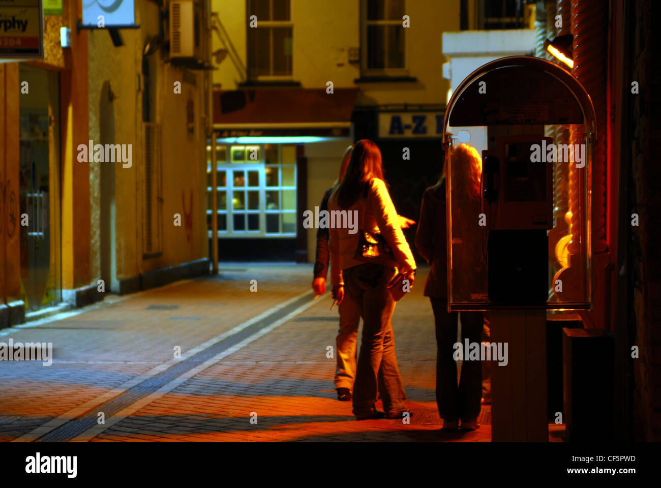 Nigh time view of women smoking outside a bar in central Cork. Stock Photo