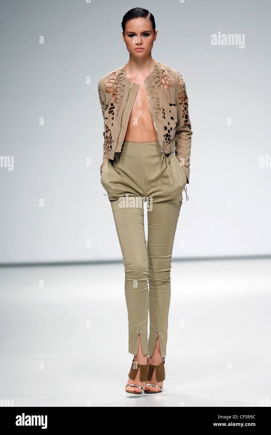 Cut away cropped brown jacket and high waisted olive skinny trousers Stock Photo