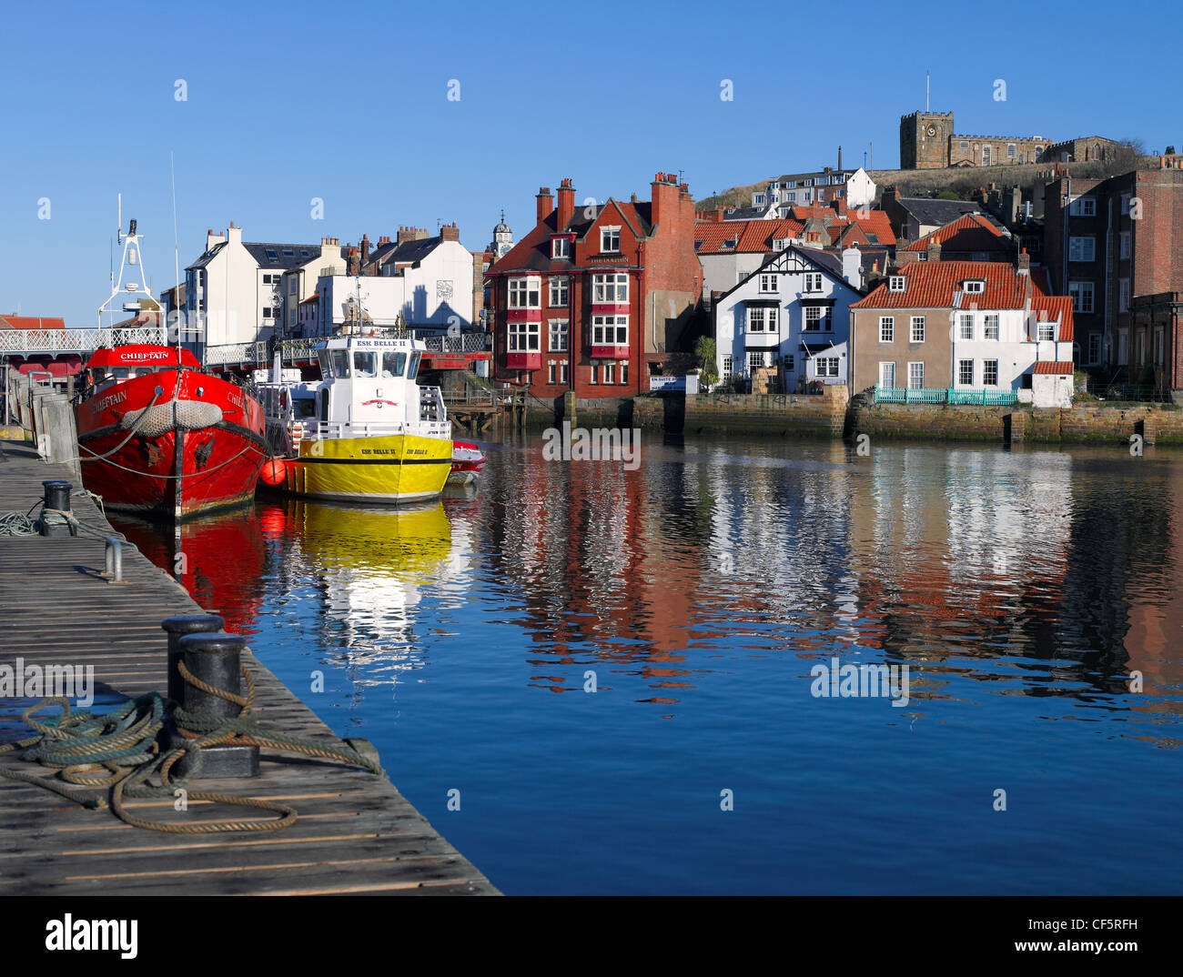 St. Mary's Church on the East Cliff overlooking fishing boats moored in Whitby Harbour. Stock Photo