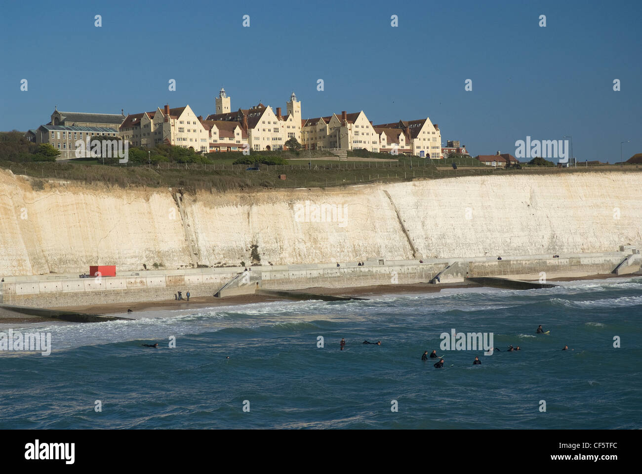 Surfers in the sea beneath white chalk cliffs near Brighton Marina. Stock Photo