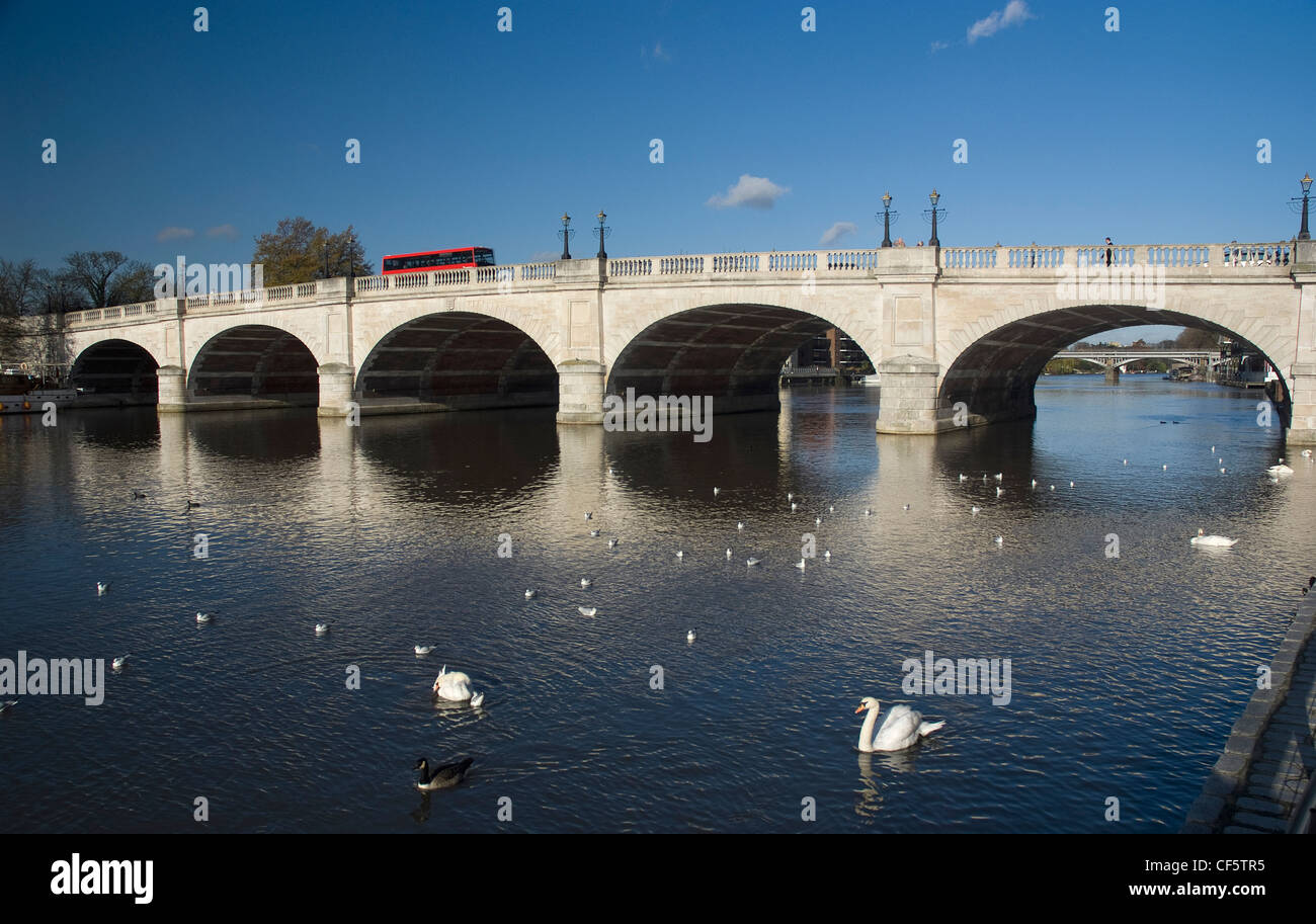 A red double decker bus crossing Kingston Bridge over the River Thames. Stock Photo