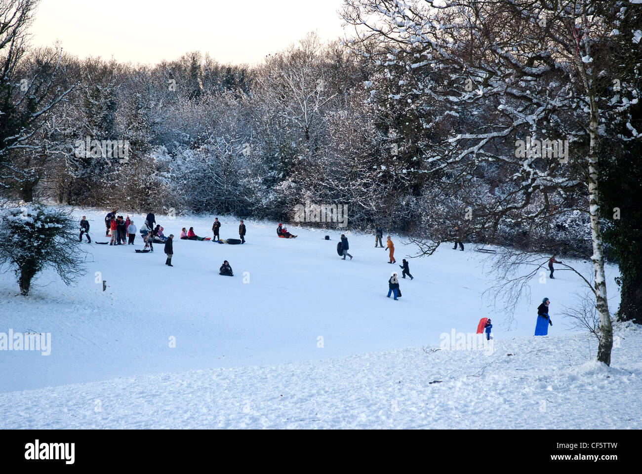 Families enjoying the snow covered slopes of Epsom Downs. Stock Photo