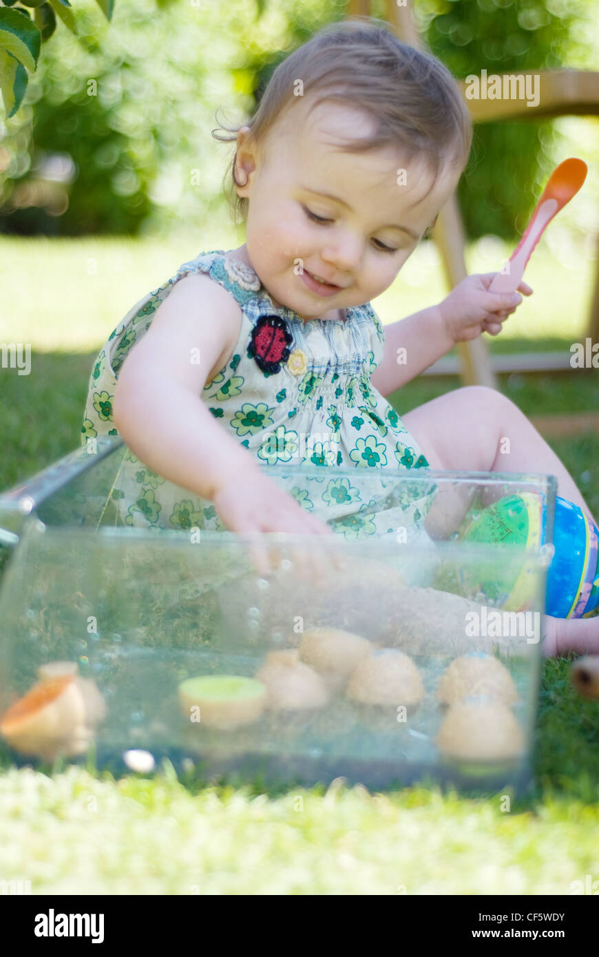 A female baby fair hair dressed in a green floral dress, sitting on the