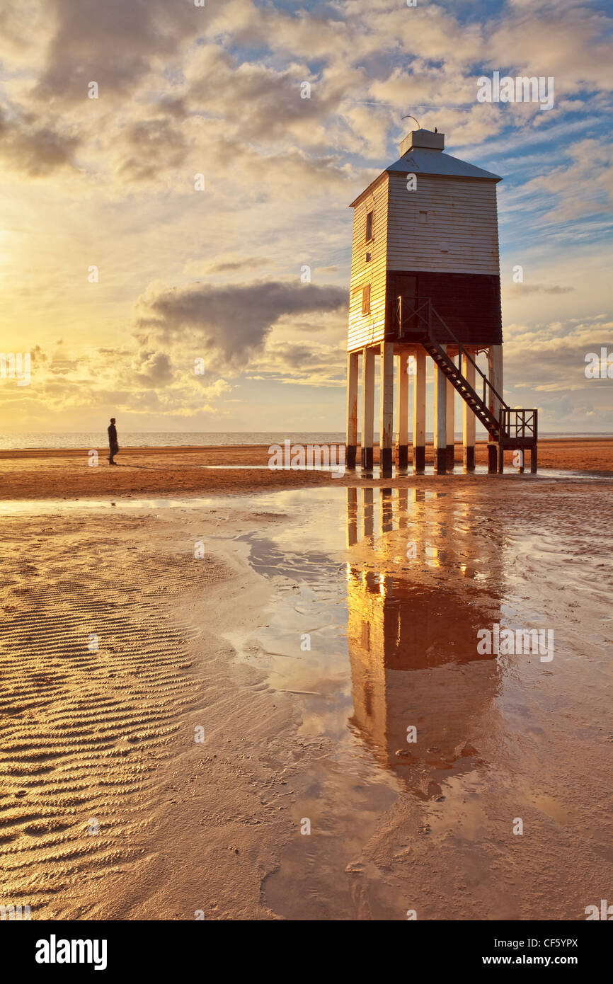 A man standing on the beach looking at Burnham-on-Sea Low Lighthouse, built by Joseph Nelson in 1832. Stock Photo