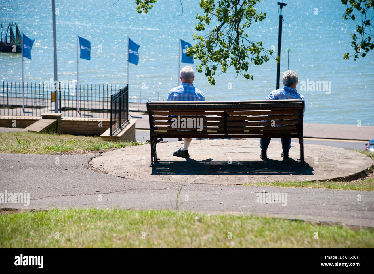 An elderly couple sitting on a bench looking out to sea at Southend-on-Sea. Stock Photo