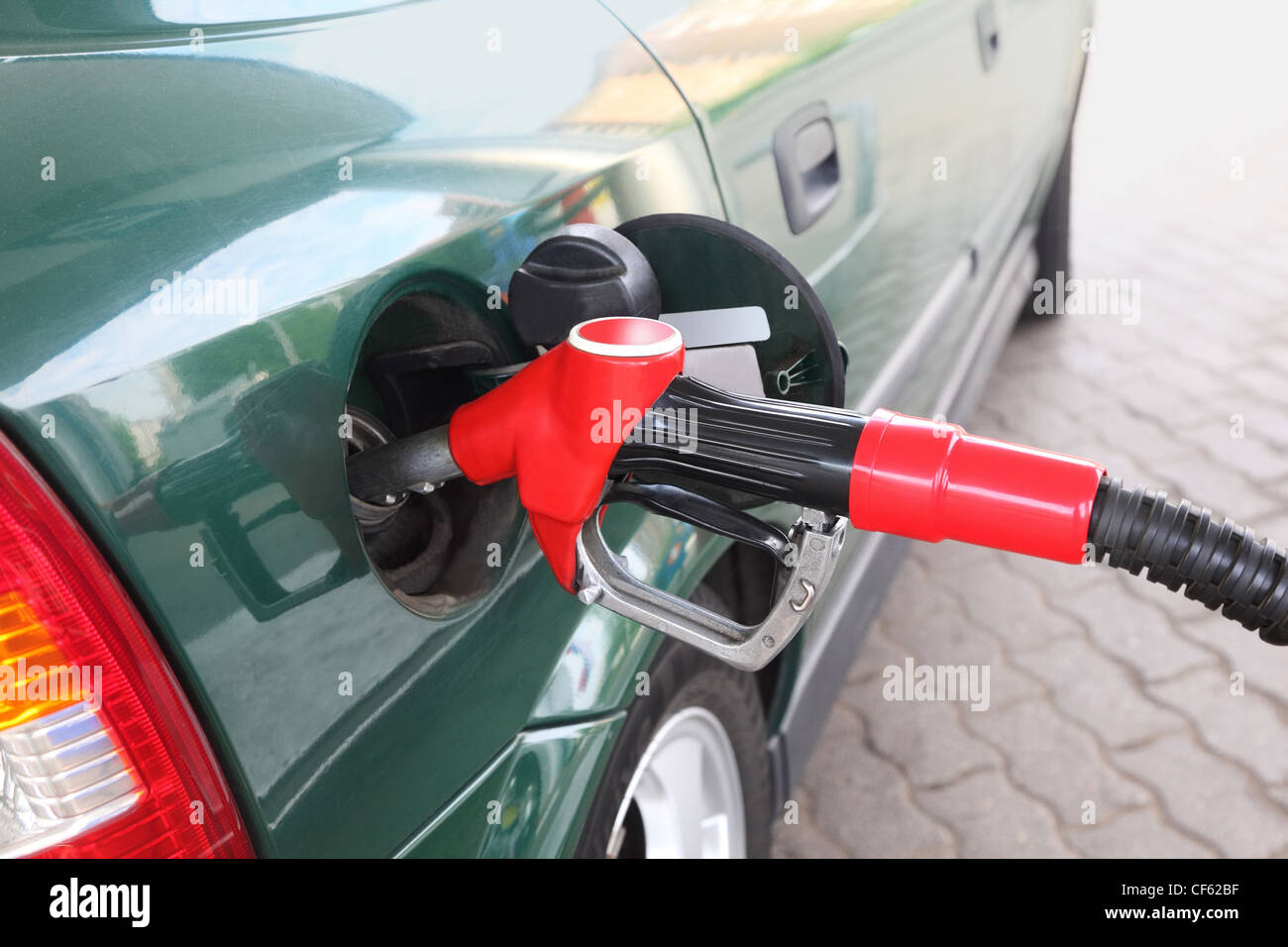 closeup of red pump for refueling filling green car on station Stock Photo