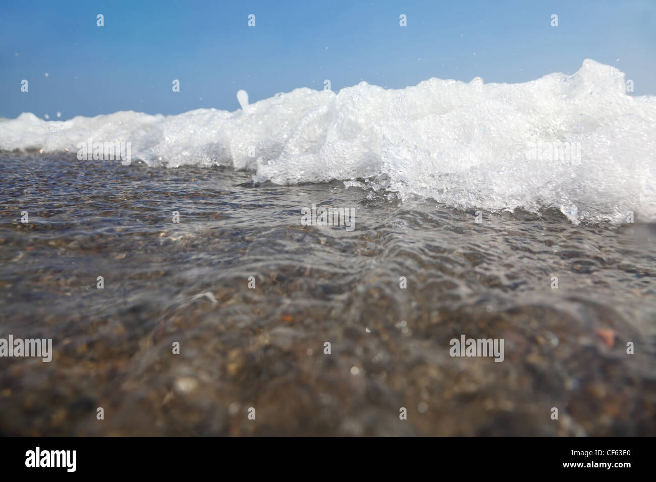 white foam of sea waves, splashes ashore. blue sky. hot summer. Stock Photo