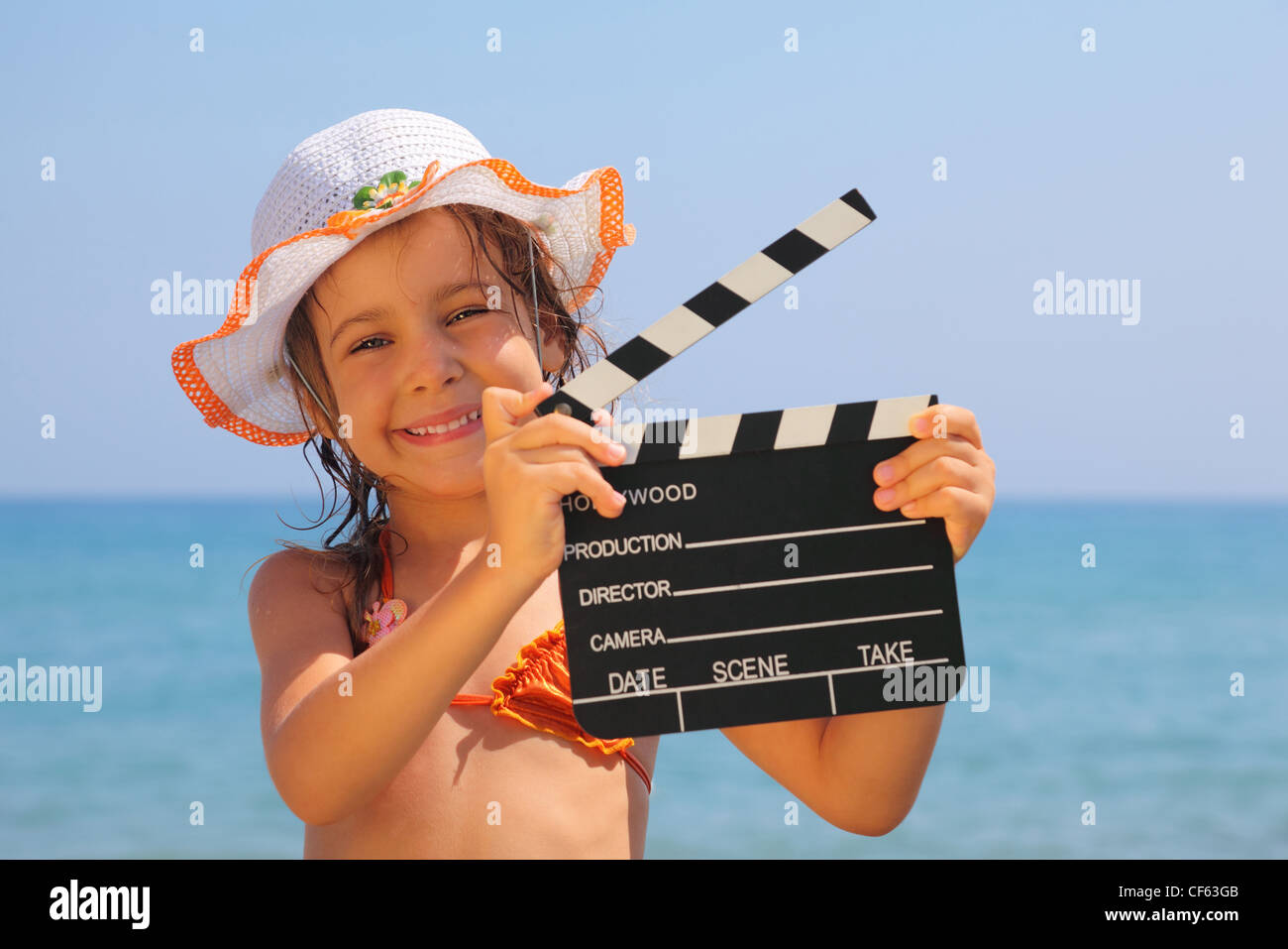 beautiful little girl standing on beach and holding clapboard. focus on girl eyes Stock Photo