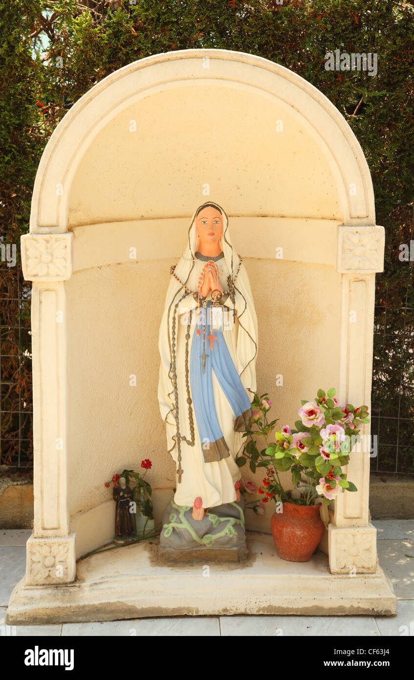 statue of Virgin Mary. located near statue of some flowers. Stock Photo