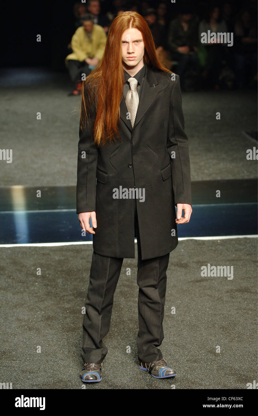 Girbaud Menswear Milan A W Red head male very long straight hair wearing a  black suit thigh length jacket, black button down Stock Photo - Alamy