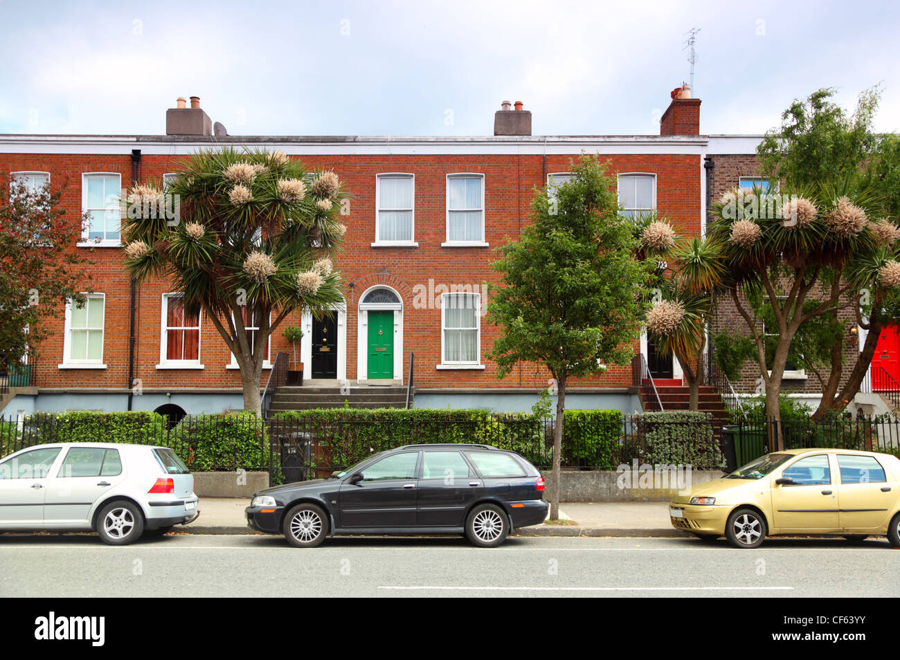 cars parked near two-story red brick house on street in Dublin, Ireland Stock Photo