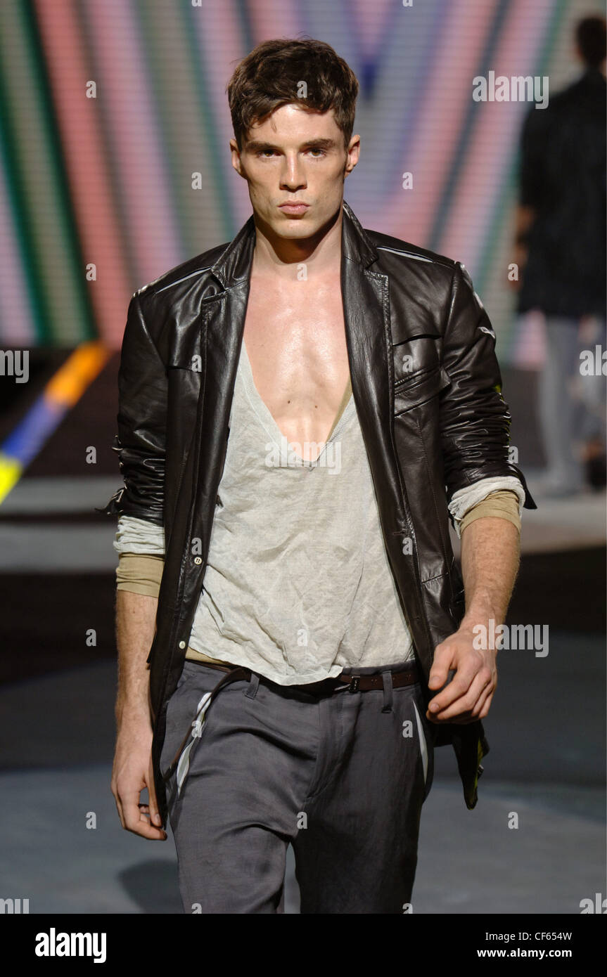 Versace Milan Ready to Wear Menswear Spring Summer Brunette male model  wearing a black leather jacket over a deep V neck T Stock Photo - Alamy
