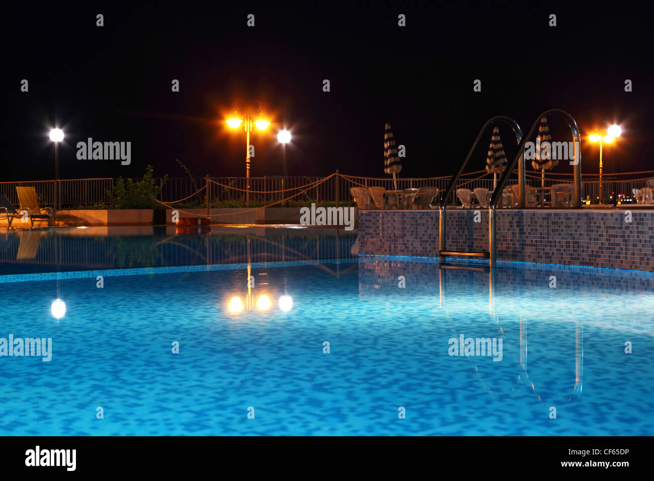 Night pool with lanterns, cafe and chairs near edge pool, focus on stair Stock Photo