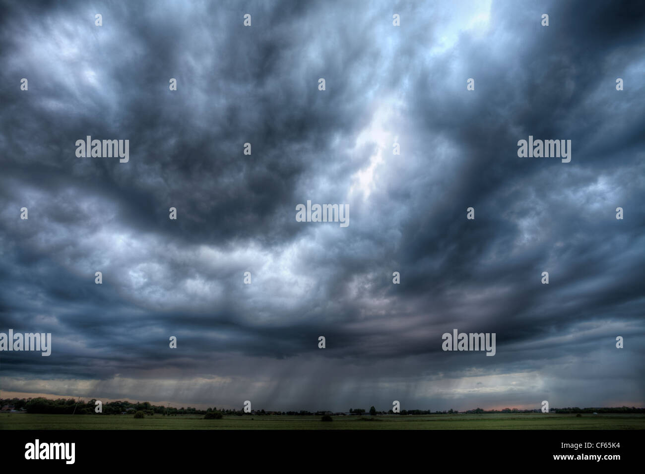Rain falling from summer storm clouds over distant fields. Stock Photo