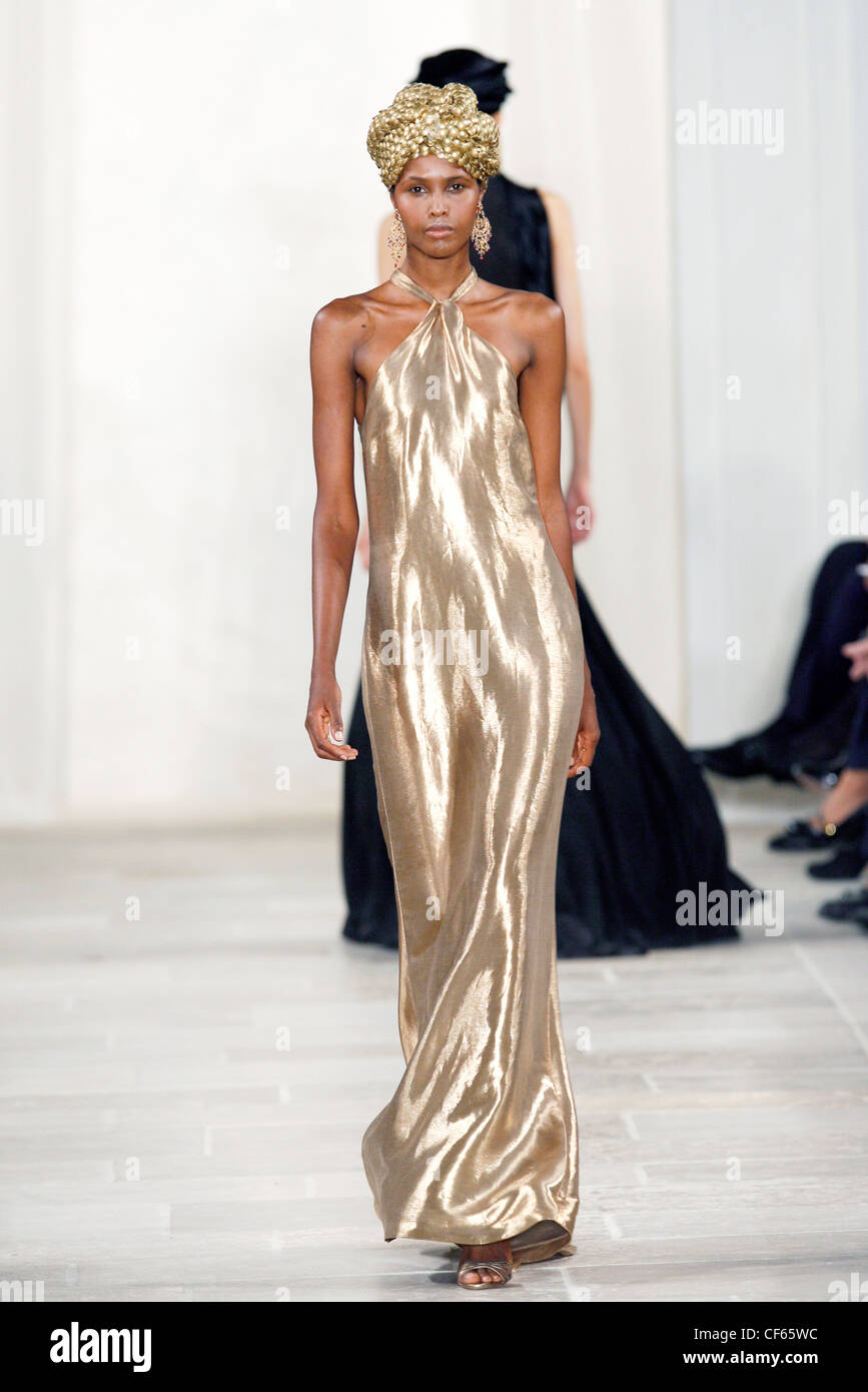 Ralph Lauren New York Ready to Wear Spring Summer Model wearing a gold lame halternecked column dress, large gold drop Stock Photo
