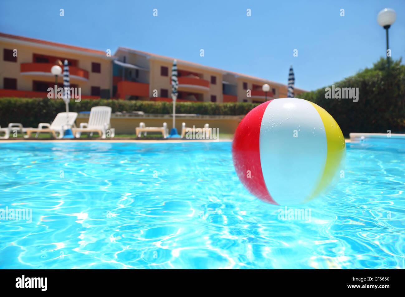 An inflatable ball lies in  pool under open-skies near cottages, underwater package Stock Photo