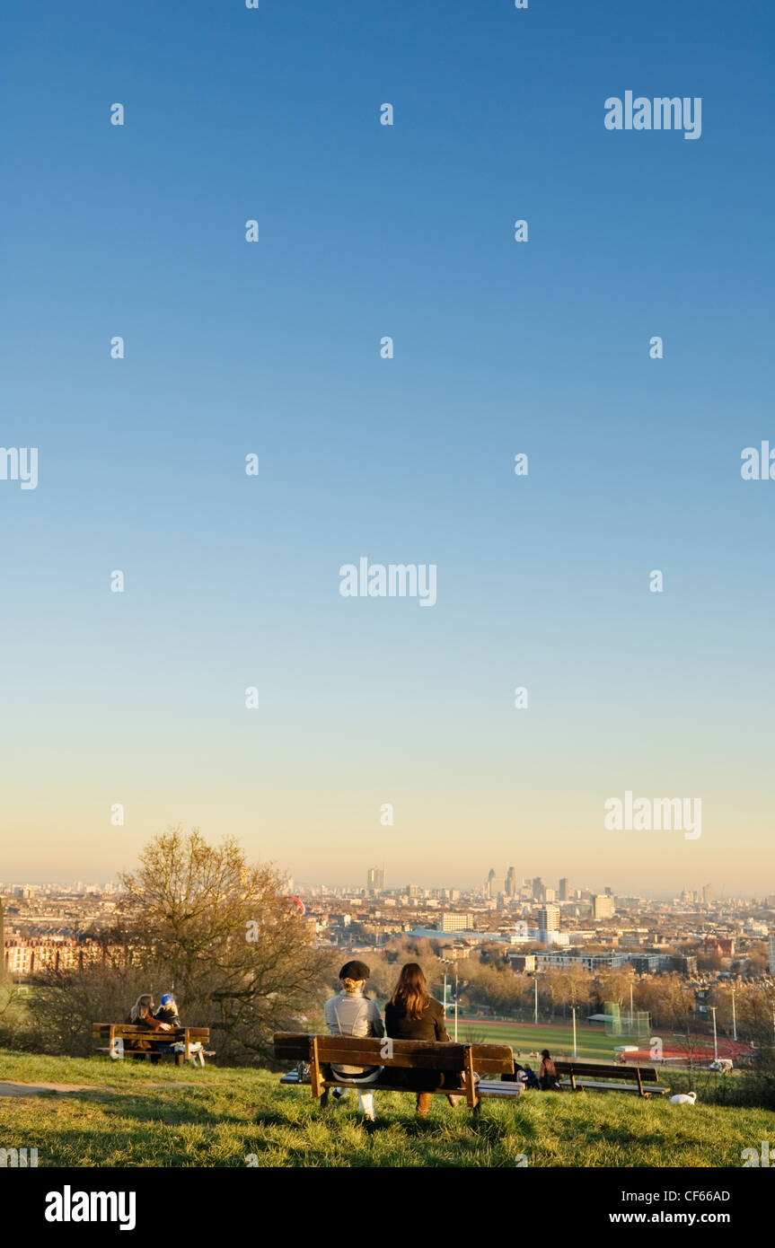 Two women sitting on a bench on Parliament Hill looking towards the skyline of the City of London. Stock Photo