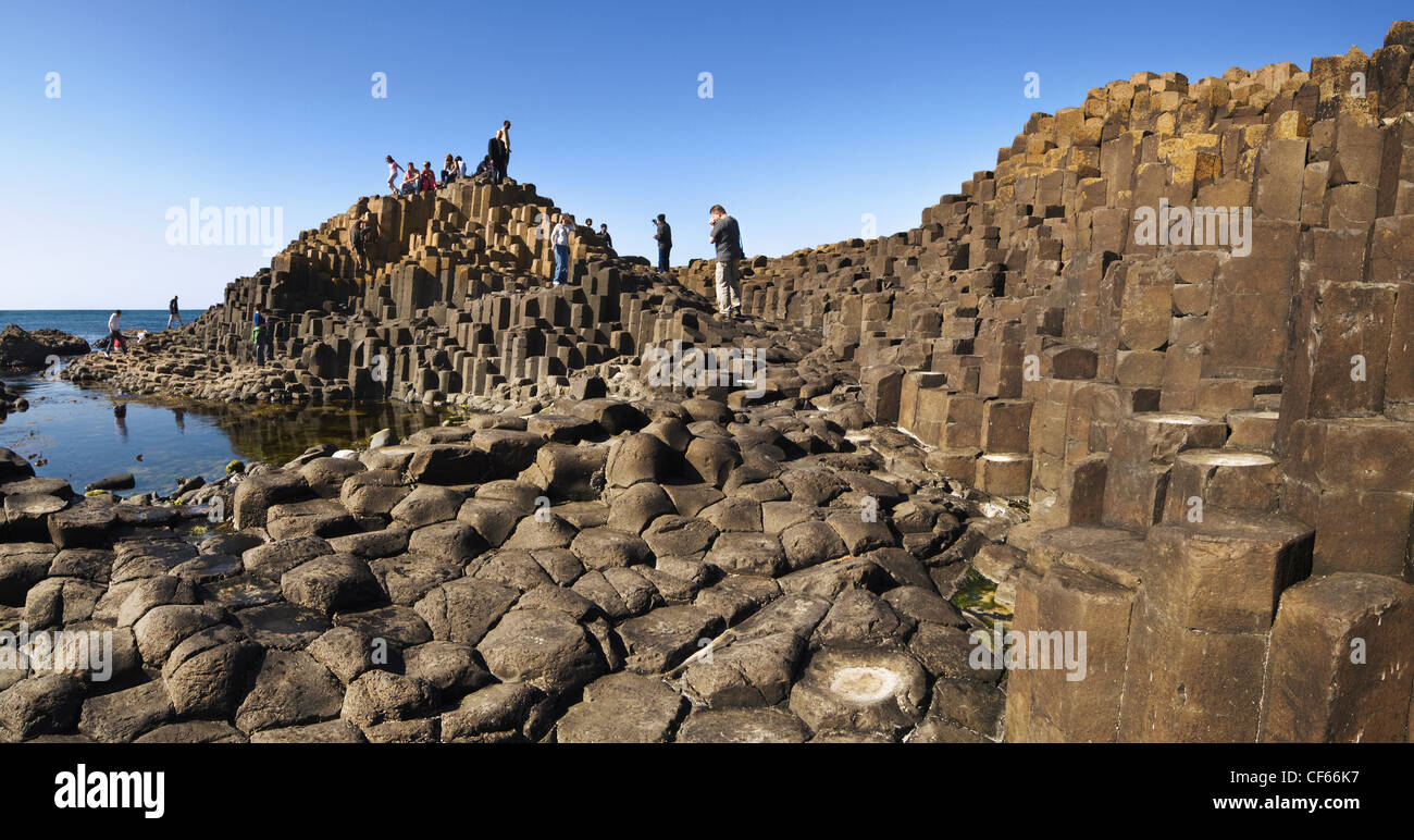 Tourists exploring the interlocking basalt columns of the Giants Causeway,  a World Heritage Site and National Nature Reserve. Stock Photo