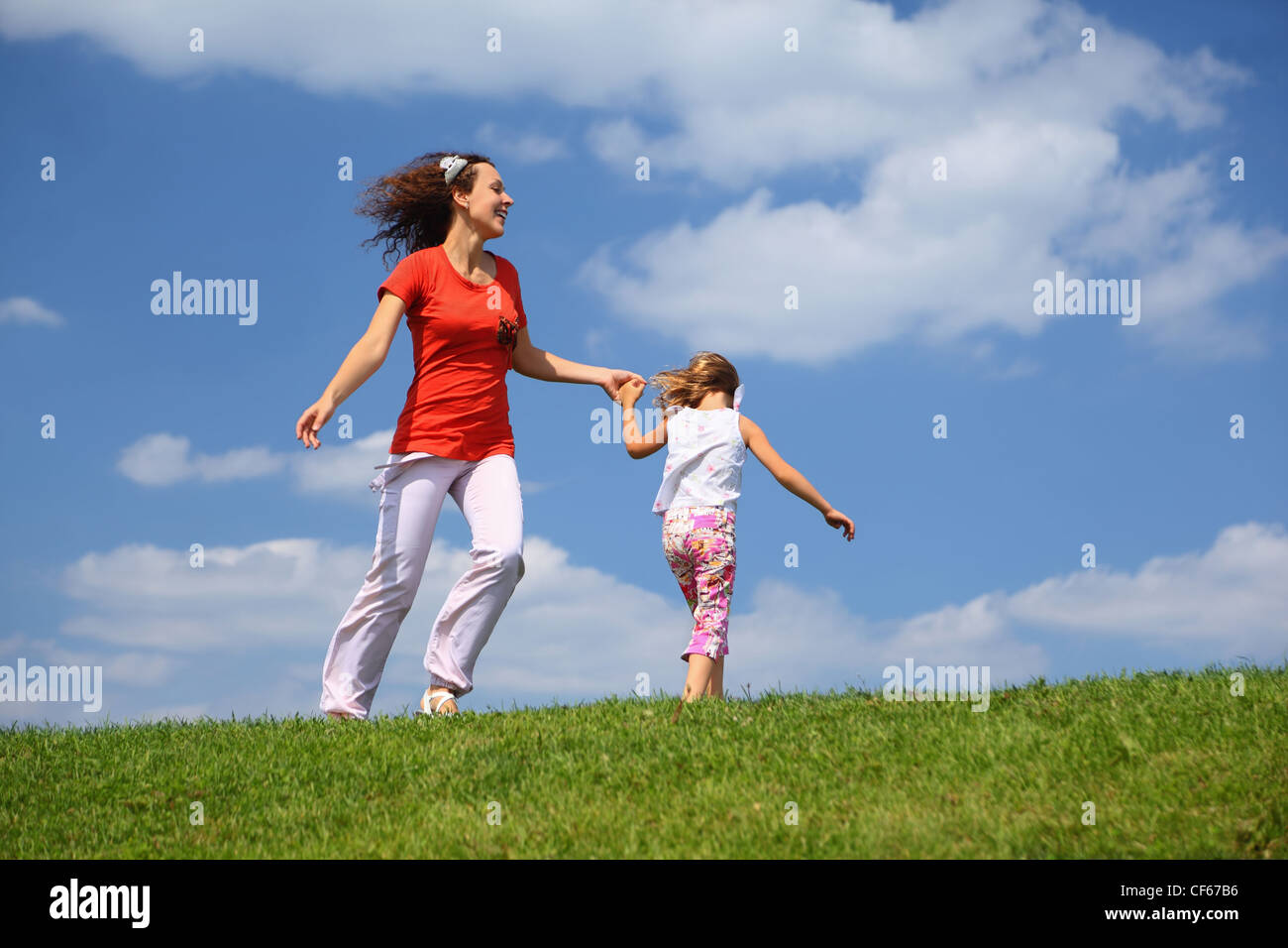 Mother with daughter hurry and play on  grass in  day-time Stock Photo